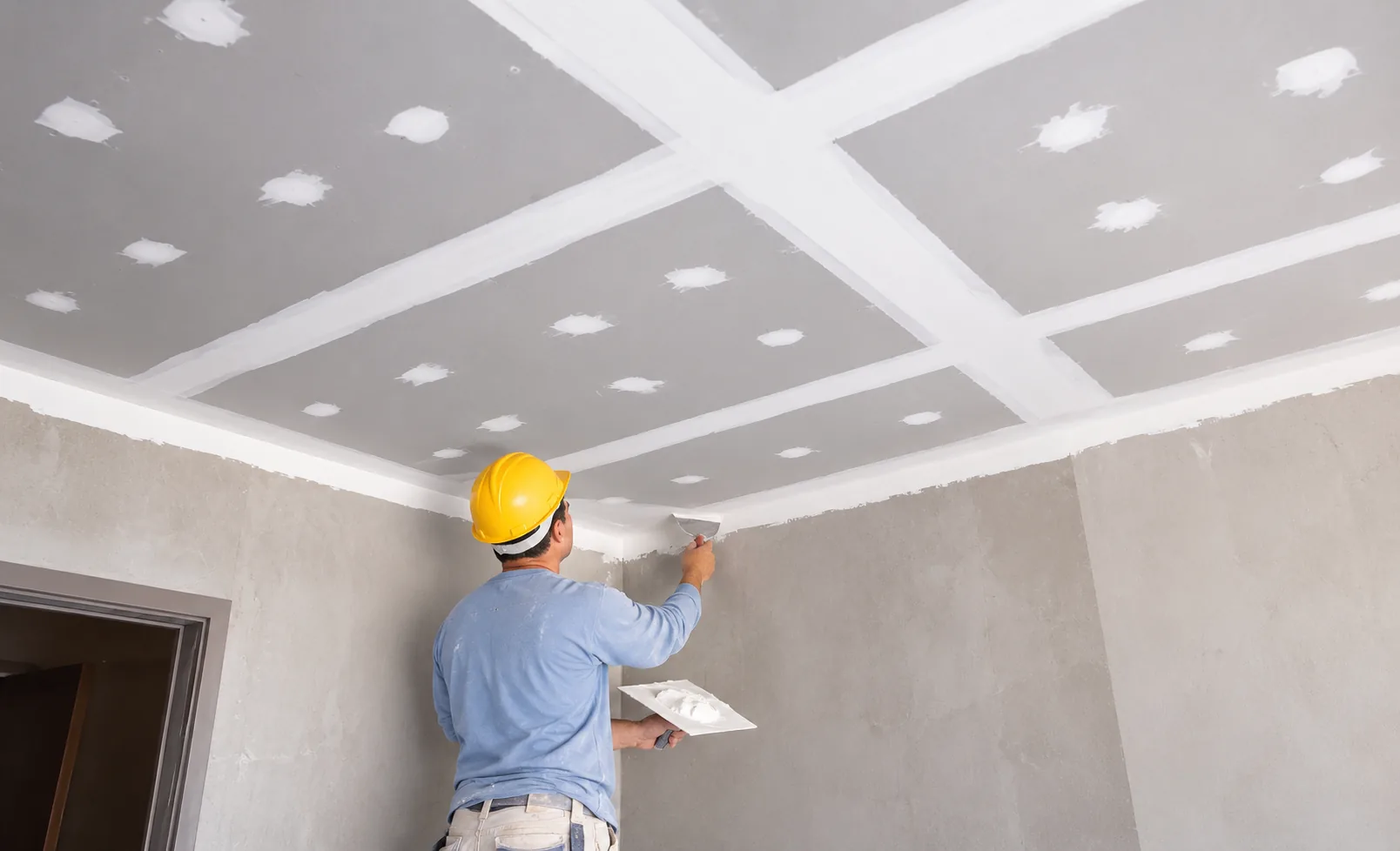 Drywall finisher applying joint compound at the ceiling edge